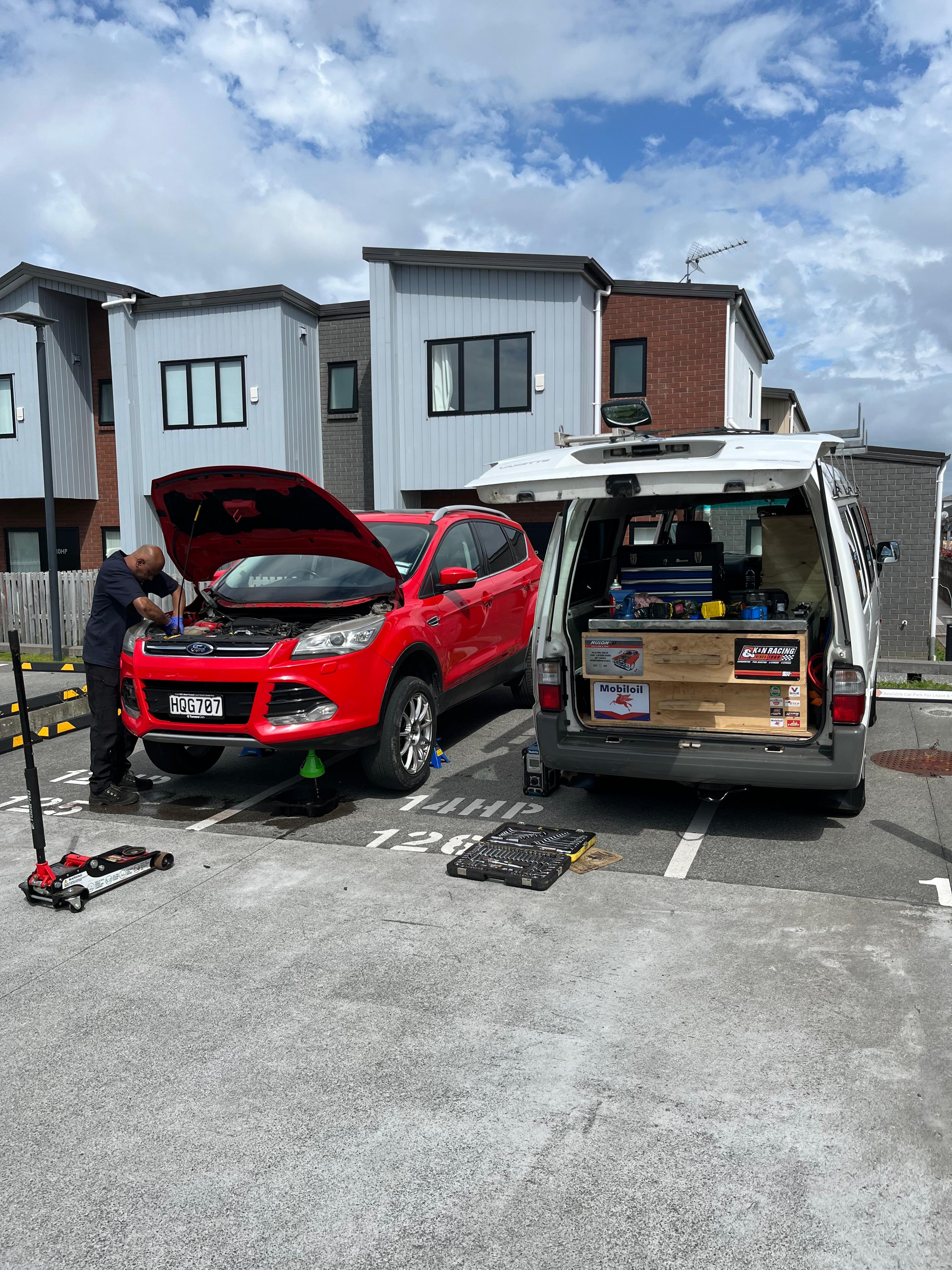 Kumie's Mobile Auto mechanic performing engine repairs on a red SUV in Auckland